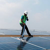 A man cleaning solar panels with a sweeper